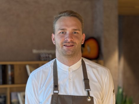 Portrait eines lächelnden Mannes mit Arbeitskleidung in einem modernen Café