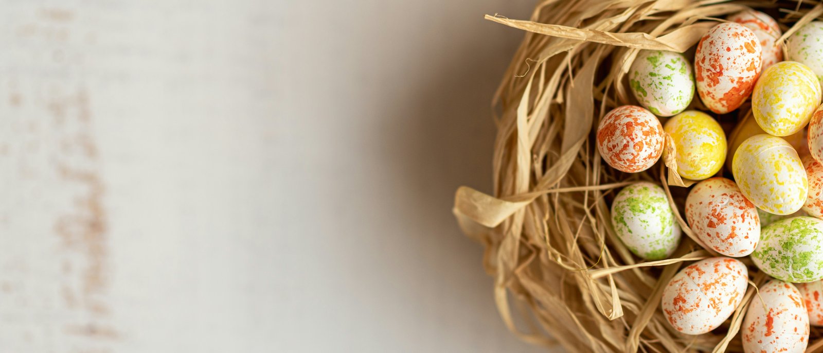 Bunter Osternest mit gefleckten Eiern auf hellem Hintergrund