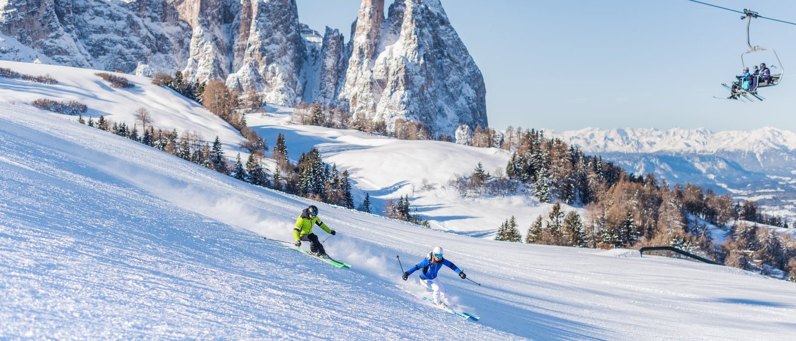 Scialpinismo per esperti Due sciatori su pista innevata con montagne innevate e seggiovia sullo sfondo