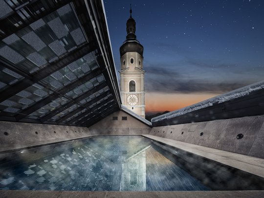 Beheizter Pool auf dem Dach mit Blick auf einen Turm bei Dämmerung
