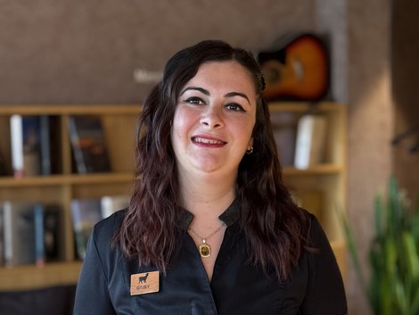 Holidays in Kastelruth at Hotel Lamm Smiling woman in black shirt with name tag in cozy room