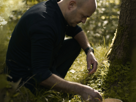 Kniender Mann mit Korb in einem sonnigen Wald