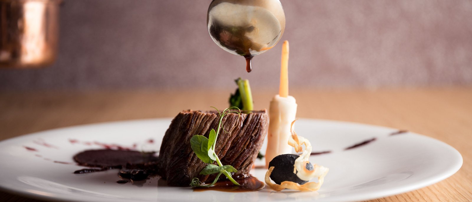 Entdecken Sie die Kräuter, die wir im Hotel Lamm verwenden! Fein angerichteter Fleischgang mit Sauce, Spargel und Gemüse auf weißem Teller