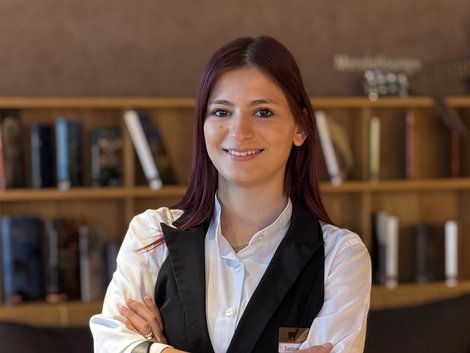 Junge Kellnerin im Restaurant mit verschränkten Armen und freundlichem Lächeln